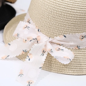 Dettaglio del nastro in chiffon floreale e fiocco sul cappello di paglia intrecciata