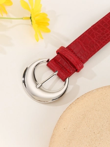 Detail of red crocodile pattern belt with a silver crescent buckle for jeans