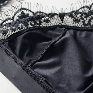 Dettaglio in pizzo di un reggiseno a triangolo nero ultrasottile con finitura satinata