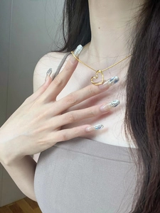 Close-up of golden open heart pendant necklace worn on a minimalist collarbone chain
