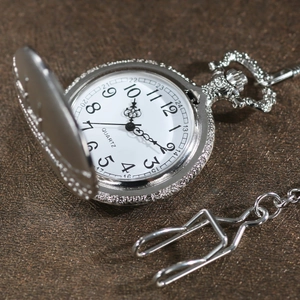 Macro shot of silver quartz pocket watch with engraved lid and white numeric dial