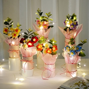 Handgefertigte Häkelblumen-Bouquets in rosa Eimern mit warmen LED-Lichterketten.