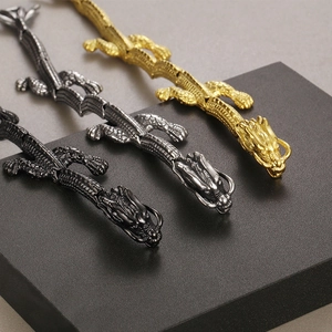 Detail of dragon-shaped bracelets in gold, silver, and black finish on a gray stand
