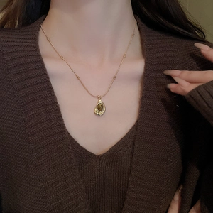 Close-up of a gold teardrop tiger eye pendant necklace worn on a woman's neck