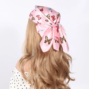 Carré de soie rose avec imprimé papillon porté sur les cheveux du mannequin