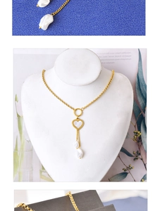 Détail du collier coeur doré avec pompons en perles blanches et pendentif cercle texturé