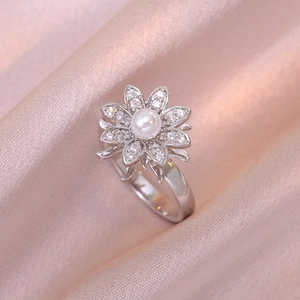 Bague fleur argentée élégante avec perle et zircons sur fond de soie rose délicat