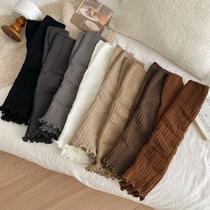Flat lay of knit leg warmers in various colors with ribbed texture and ruffle edges