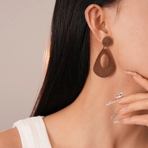 Gros plan de boucles d'oreilles gouttes marron avec texture floquée mate sur le modèle