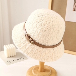 Detail of beige knit bucket hat with brown faux leather belt and gold heart charm