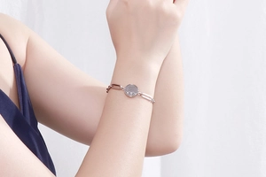 Close-up of elegant silver chain bracelet with round elephant charm worn on wrist