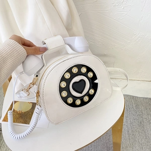 Detail of creative white patent leather crossbody bag in a vintage telephone shape