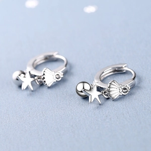 Macro shot of silver starfish and shell charms on elegant minimalist hoop earrings