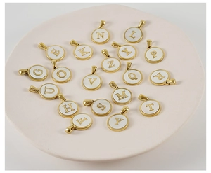 Close-up of golden stainless steel round letter pendants with white shell inlay details