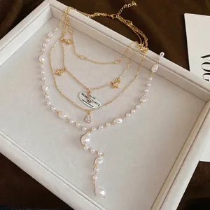 Layered gold necklace with baroque pearls, star charms, and a teardrop gemstone pendant