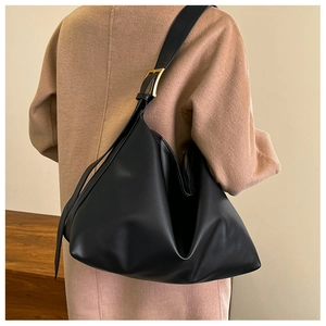 Detail of black leather hobo bag with gold buckle on a model wearing a wool coat