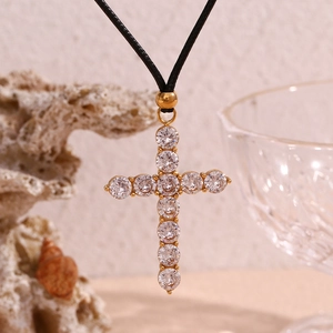 Macro shot of 18K gold plated cross pendant with white zircons on black rope chain