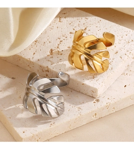Detail von 18K Gold und Silber Monstera Blattringen auf Stein- und Seidenhintergrund