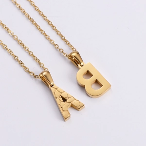 Detailed view of 18K gold plated letter A and B pendants with textured and polished finishes