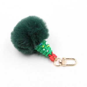 Detail of a green plush pompom and festive Christmas tree keychain with a gold metal clasp