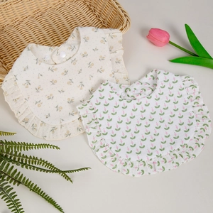 Flat lay detail of ruffle edge cotton gauze baby bibs with floral and tulip prints