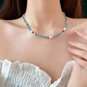 Bohemian pearl and blue gemstone necklace with metallic spacers on a model neck