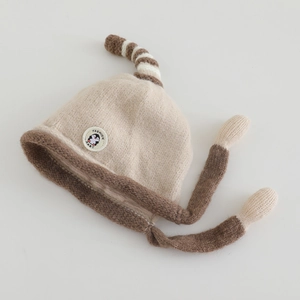 Detailed view of baby knit hat with penguin patch and striped tail design in beige