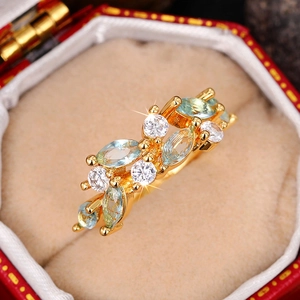 Detailed close-up of 18K gold ring with marquise aquamarine and zircon in vintage red box
