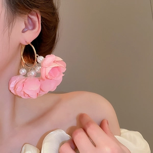 Detail of pink fabric flower earring with pearls and gold hoop on a model's ear