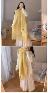 Detailed close-up of a soft yellow winter scarf featuring classic tassel fringe design