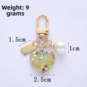 Detail view of heart keychain with green glitter pendant, white pearl, and gold clasp