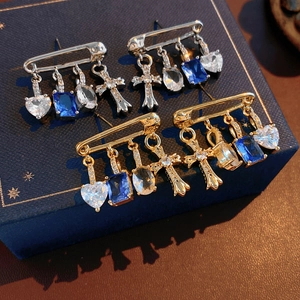 Detail view of pin-shaped heart and cross earrings with blue zircon in gold and silver finish