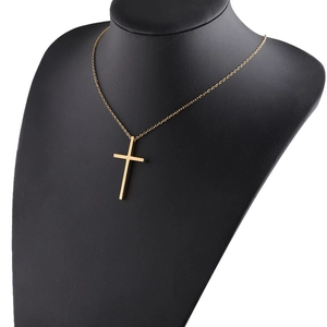 Detailed view of a polished gold cross pendant on a black mannequin neck with a thin chain