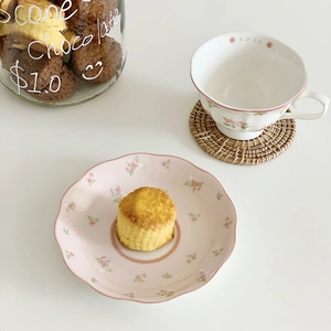 Top view of pink rose pattern ceramic coffee cup and saucer set on white surface