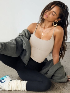 Detail of a beige slim fit tank top styled with high-waist black leggings and a gray hoodie