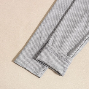 Detail of grey ribbed knit long sleeve bodysuit showing sleeve cuff texture and fabric