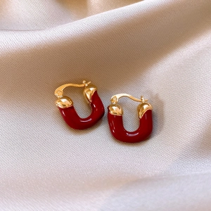 Detail of red strawberry U-shaped hoop earrings on elegant silk fabric background