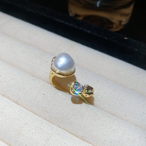Close-up of gold vintage ring with baroque pearl and zircon on beige velvet tray