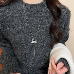 Detail of silver reindeer pendant with crystal pavé on a grey knitted sweater