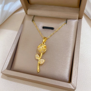 Close-up of sparkling gold rose pendant necklace set in a luxury jewelry box