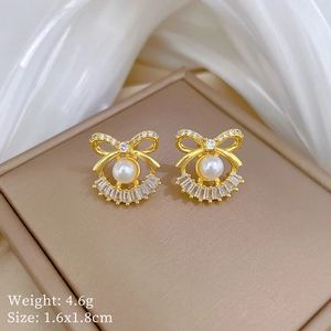 Detail view of pearl bow earrings on a leather box with size and weight specifications