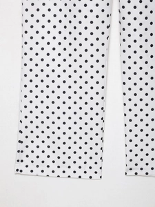 Détail du pantalon blanc à pois noirs montrant les ourlets soignés au bas des jambes