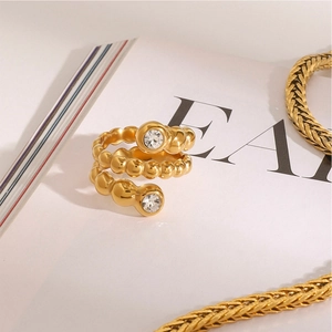Détail d'une bague spirale dorée sertie de zircons et texture métal perlé