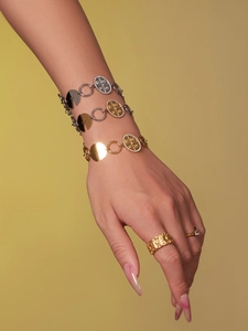 Detail showing layered gold and silver stainless steel disc bracelets with zircon inlay