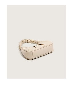 Detailed side and bottom view of beige pleated handbag with ruched handle texture