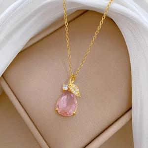 Détail d'un pendentif en pierre rose poire avec feuille d'or et cristaux pavés