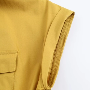 Détail de la robe en popeline jaune moutarde montrant les coutures d'épaule et la poche
