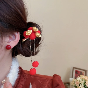 Close-up of Chinese style hair clip with red pompom, gold ingots and long tassels
