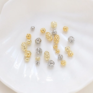 Macro shot of gold and silver hollow metal beads on a white shell plate for DIY jewelry