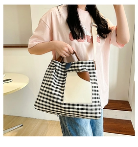 Detail of checkered canvas tote bag with cream pocket and brown leather handles